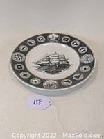Front view of Wedgwood commemorative plate showing ship Highlander and flags rim