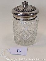 Clear scalloped cut glass jar with diamond and crosshatch patterns, topped with a detailed sterling silver lid and a purple jewel finial.