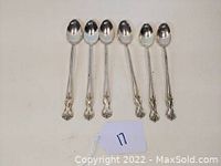 Six Wm. Rogers ice tea spoons aligned in a single row showing front side with floral handle detail.