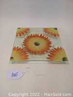 Front view of the square glass dish with orange sunflower design in corners and center depression
