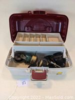 Open white and maroon tackle box showing fishing reels and compartment tray
