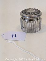 Front angled view of the Victorian clear glass cosmetics jar with its ornate sterling silver lid featuring repoussé floral Art Nouveau design.