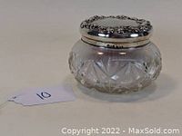 Front and side view of Victorian cut glass powder jar with silver lid showing cut glass designs and floral repousse details on lid.