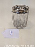 Front view of Victorian style dresser jar showing clear pressed glass and ornate silver-tone metal lid with patterned holes