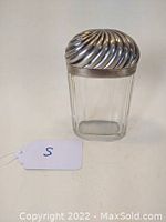 Front view of the Victorian glass oval jar with sterling silver swirled dome lid. Clear ribbed glass body and prominently swirled silver dome lid are visible.