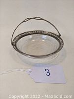 View of vintage etched glass dish with sterling silver reticulated rim and hinged handle from front angle.