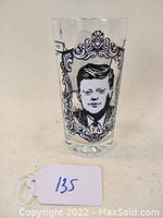 Front view of tumbler showing portrait of John F. Kennedy in black and white print inside decorative ornate frame.