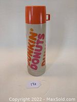 Front view showing full Dunkin Donuts logo in vibrant orange and pink on white body, orange cap with handle.