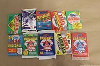 Top view showing all 10 unopened baseball wax packs from various brands and years on a beige surface.