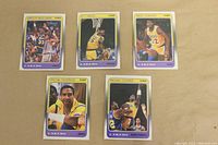 Five 1988 Fleer LA Lakers basketball cards displayed flat including Magic Johnson, Kareem Abdul-Jabbar, AC Green, Michael Thompson, Michael Cooper
