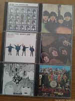 Photo of nine Beatles studio album CD covers including Help!, Rubber Soul, Revolver, Sgt. Pepper's Lonely Hearts Club Band, Magical Mystery Tour, Abbey Road, The Beatles double White Album, Beatles For Sale.