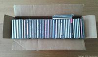 Open top view of cardboard box containing over 45 CDs arranged neatly side by side.