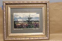 Full view of framed print showing house, lupines, tree and sky with ornate gold wooden frame.
