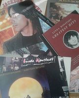 Photo showing a mixed pile of LPs including Jackson Browne and Linda Ronstadt albums, cover conditions vary with some wear visible.