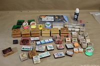 Overview of a large assortment of wooden and plastic stamp pads, several with colorful printed themes and some ink bottles visible