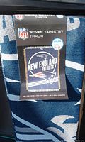 Label showing NFL logo, New England Patriots logo, and throw details (woven tapestry, size 60x48 inches).