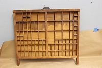 Full view of the rectangular wooden printer's type drawer case with numerous small compartments and metal hanger for wall display.