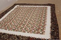 Full view of large patchwork quilt laid out flat on the floor showing overall design and size.