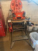 Orange Kmart 6-inch bench grinder mounted on Black & Decker Workmate 225 folding workbench in workshop setting. Extension cord reel mounted on grinder.