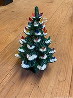 Photo of the ceramic lighted Christmas tree with colorful bulbs and snow detailing on a wood floor