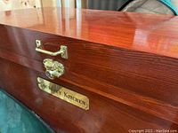 Close-up of the lock and brass plaque on the wooden cedar tack box reading 'Courtney Kitchen'.