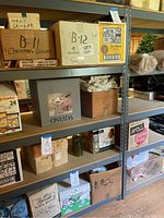 Front view of five-tier metal and board shelving unit loaded with various cardboard boxes and items not included in sale.