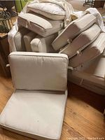 Pile of taupe outdoor cushions showing both seat and back cushions