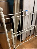 Off-white or cream painted metal full-size headboard with decorative floral and ball finial details.