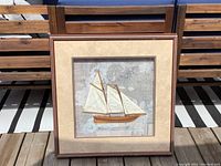 Framed vintage two-mast schooner model sailing boat with white sails on early sea map background.