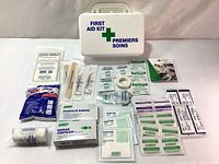 Full contents of new small portable first aid kit box laid out with box in background