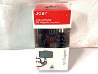 Front view of the Joby GripTight ONE GP Magnetic Impulse tripod in retail packaging showing the tripod, Bluetooth remote, and phone mount.