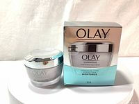 Photo of Olay Luminous Tone Perfecting Cream jar next to its box showing front labels and packaging.
