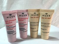 Front view of four 30ml tubes: two pink Nuxe Melting Cleansing Gels and two beige Nuxe Rêve de Miel Hand and Nail Creams.