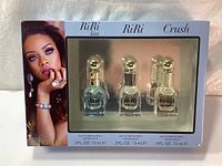 Front view of the Rihanna perfume gift box showing three perfume bottles: RiRi Kiss, RiRi, and Crush, with image of Rihanna on left side of box.
