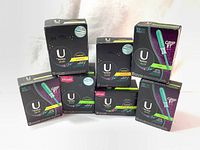 Lot of 8 boxes of U by Kotex Sleek tampons with black packaging and green elements, varying tampon absorbency levels shown in the boxes