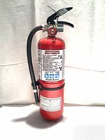 Photo of red Sunbeam Flag 9lb ABC powder fire extinguisher with attached black hose and pressure gauge, showing full unit from side.