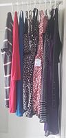 Photo of 10 women's dresses hanging on a rod, varied colors and patterns including striped, floral, polka dots, and solid colors.