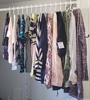Lot of 15 women's blouses hanging on a rod, showing variety of colors and patterns