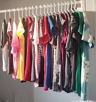 20 assorted women's shirts and blouses hanging on a rack showing a variety of colors and styles.