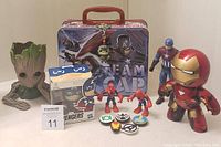 Photo showing Team Cap lunch box, Groot planter, Captain America, Iron Man figurines, two Spider-Man figures, and a Funko Pop Groot key chain attached to lunch box