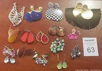 Photo of 15 pairs of women's custom earrings showing diverse materials and styles including rhinestones, wood, beads, and fringe.