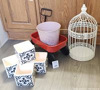 Full view of gardening items including mini wagon, bird cage, purple pot and four square ceramic pots