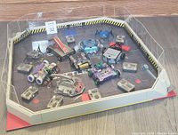 Full view of the assembled battle arena containing seven robots and eight remote controls arranged inside.