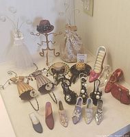 Overview of the lot showing miniature shoes, dress-shaped wall hooks, two dress jewelry holders, and a small hat stand.
