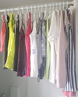 Full lot of 16 women's tank tops and blouses hanging on a clothing rod, showing variety of colors and styles.