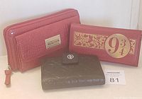 Three women's wallets displayed together: Kenneth Cole Reaction red faux crocodile zip wallet, black embossed Giani Bernini wallet, and red Harry Potter Hogwarts Express 9 3/4 themed wallet.