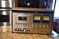 Front view of Akai GXC-510D showing metal faceplate, wooden housing, VU meters and control layout