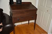 Front and side view of closed slant-top desk showing tapered turned legs and single drawer