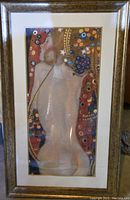 Full view of the framed art print, showing the entire image in the frame with the seated woman and ornamental floral background.