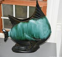 Side angle view of large Blue Mountain Pottery Angel Fish figurine showing green and black glaze, stylized fins, and base.